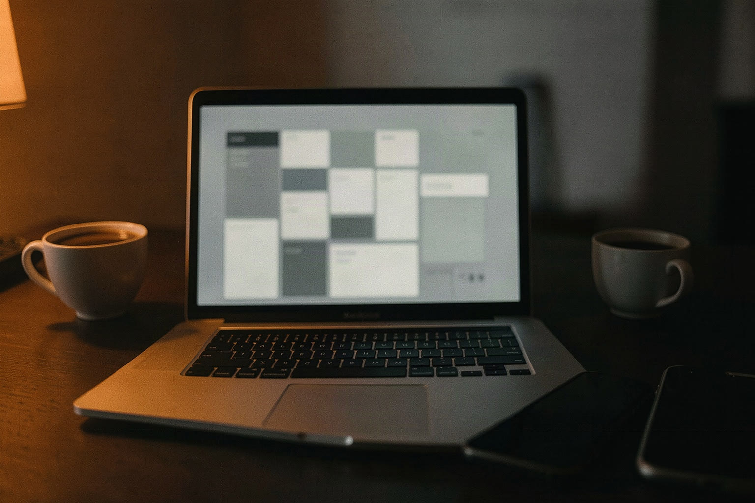 Notebook auf einem dunklen Schreibtisch, daneben eine Tasse